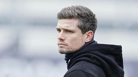 Trainer Robert Klauß steht vor einem Spiel auf dem Spielfeld.