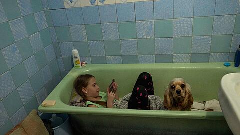 Während in Lwiw eine Luftsirene ertönt, sitzt Zlata-Maria Shlapak mit ihrem Hund Letti in einer Badewanne.