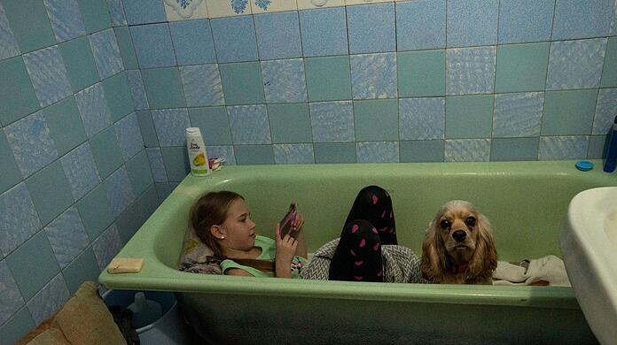 Während in Lwiw eine Luftsirene ertönt, sitzt Zlata-Maria Shlapak mit ihrem Hund Letti in einer Badewanne.