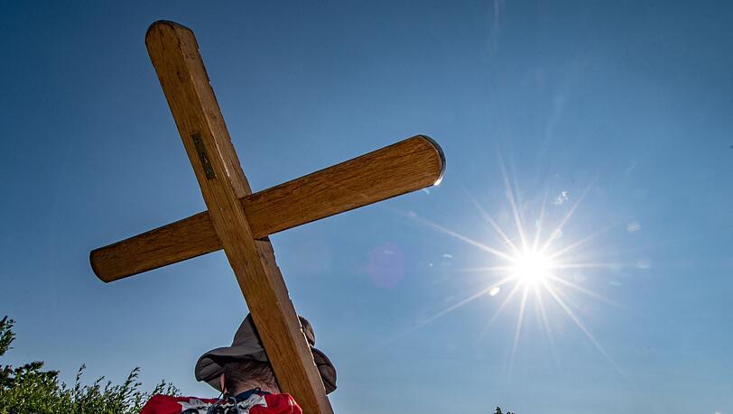 Ein Pilger trägt während einer Fußwallfahrt ein Holzkreuz.