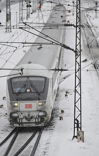 Dieser Zug fährt in Rosenheim über die verschneiten Gleise.