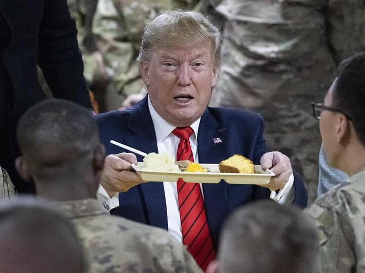 US-Präsident Donald Trump hält bei einem Besuch von amerikanischen Truppen ein Tablett mit Essen in der Hand.