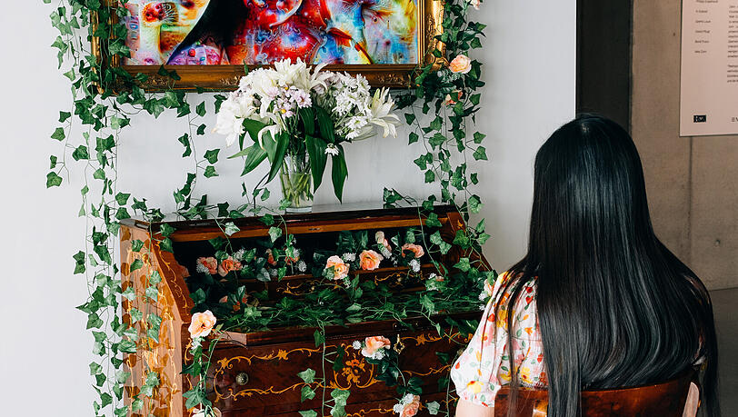 „Bildschirm, Bildschirm an der Wand, wer ist....?“ Neun Sekunden braucht die KI, um das Porträt eines Besuchers, der sich vor der Biedermeierkommode niedergelassen hat, in ein florales Tierbild zu verwandeln: die digital-analoge Installation eines KI- und Bilderkennungsexperten aus der Rüstungsindustrie, der sich als Künstler KI Kobolt nennt. „Bildschirm, Bildschirm an der Wand, wer ist....?“ Neun Sekunden braucht die KI, um das Porträt eines Besuchers, der sich vor der Biedermeierkommode niedergelassen hat, in ein florales Tierbild zu verwandeln: die digital-analoge Installation eines KI- und Bilderkennungsexperten aus der Rüstungsindustrie, der sich als Künstler KI Kobolt nennt.