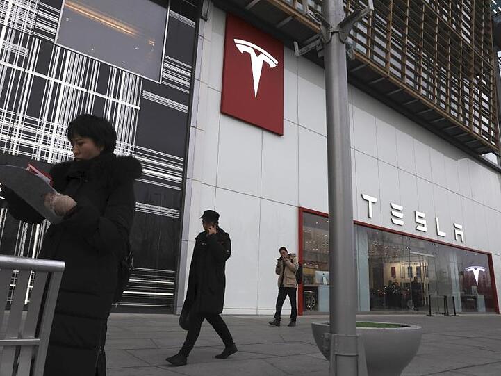 Fußgänger gehen an einer Tesla-Filiale in Peking vorbei.
