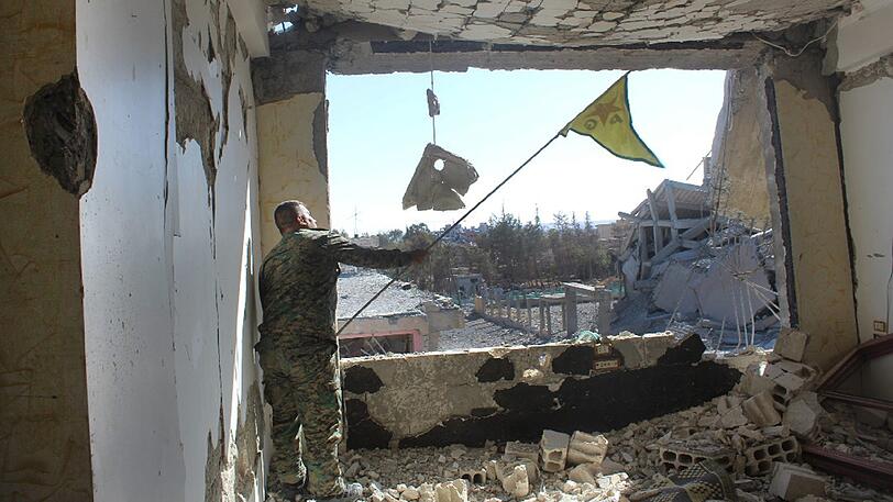 SDF-Kämpfer schwenkt im zurückeroberten Al-Rakka eine kurdische Flagge