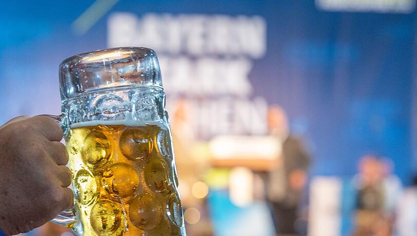 Ein Mann hält eine Maß Bier hoch.