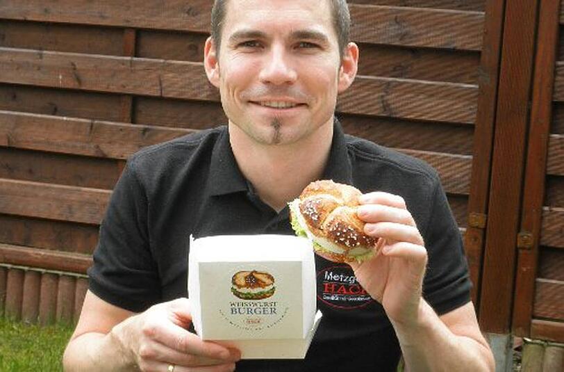 Metzgermeister Steffen Schütze von der Metzgerei Hack aus Freising mit seiner neuen Kreation - dem Weißwurstburger.