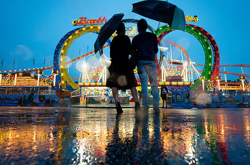 Schee wars trotz an Regn: Ein Pärchen blickt am Samstagabend auf dem Oktoberfestgelände auf eine Achterbahn.
