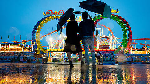Schee wars trotz an Regn: Ein Pärchen blickt am Samstagabend auf dem Oktoberfestgelände auf eine Achterbahn.