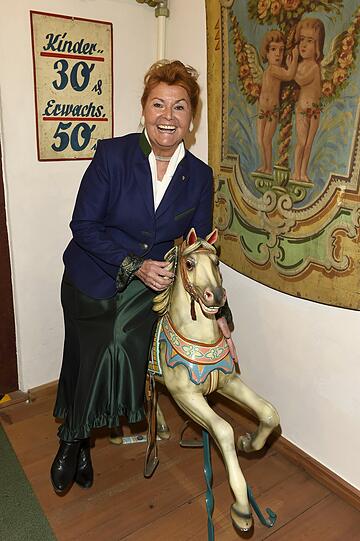 Gabriele Weishäupl im Bier- und Oktoberfestmuseum mit einem antiken Karussellpferdl