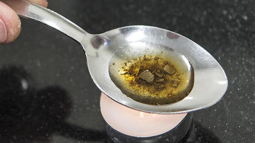 Ein Mann "kocht" sich auf einem Löffel die Dosis für einen Schuss Heroin.