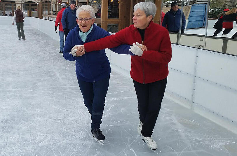 Zwei Damen versuchen sich schon mal auf der Eisflaufbahn am Stachus.