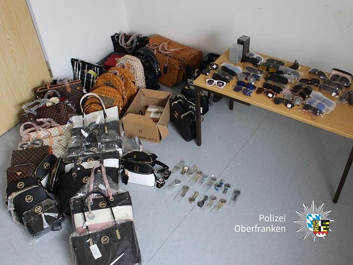 Sichergestellte gefälschte Handtaschen, Geldbeutel, Uhren, Sonnenbrillen und Parfüms. Foto: --/Polizei Oberfranken