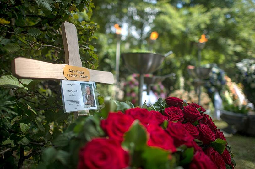 Das Blumengesteck der Familie und ein Kreuz sind nach der Beerdigung auf dem Grab des Musikers Max Greger auf dem Waldfriedhof in Grünwald zu sehen.
