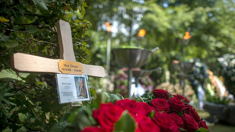 Das Blumengesteck der Familie und ein Kreuz sind nach der Beerdigung auf dem Grab des Musikers Max Greger auf dem Waldfriedhof in Grünwald zu sehen. Das Blumengesteck der Familie und ein Kreuz sind nach der Beerdigung auf dem Grab des Musikers Max Greger auf dem Waldfriedhof in Grünwald zu sehen.