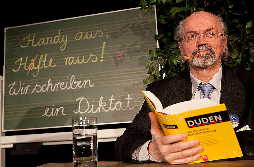 Werner Scholze-Stubenrecht, Chef der Duden-Redaktion, sitzt in einem Gymnasium in Frankfurt am Main beim Finale des Schreibkampfes "Frankfurt schreibt! - Der große Diktatwettbewerb" als Jury-Vorsitzender auf der Bühne.
