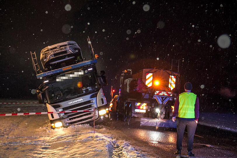 Ein Autotransporter rutscht aufgrund der schneeglatten Fahrbahn in den Graben