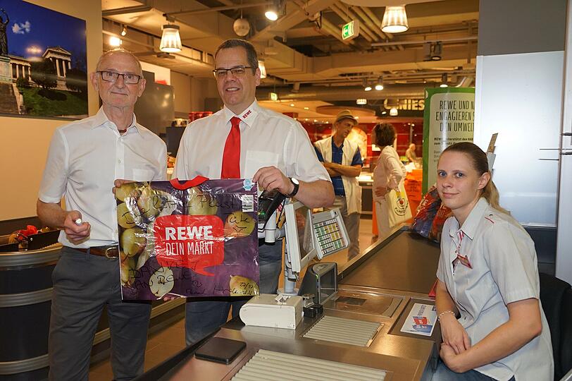 Plastik ade: Kommunalreferent Axel Markwardt und Rewe-Marktchef Jörg Löffler lassen die letzte Plastiktüte übers Band laufen.