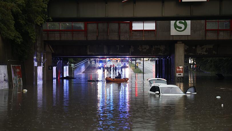 Einsatzkräfte der Feuerwehr gelangen per Schlauchboot zu Autos in einer überschwemmten Unterführung.