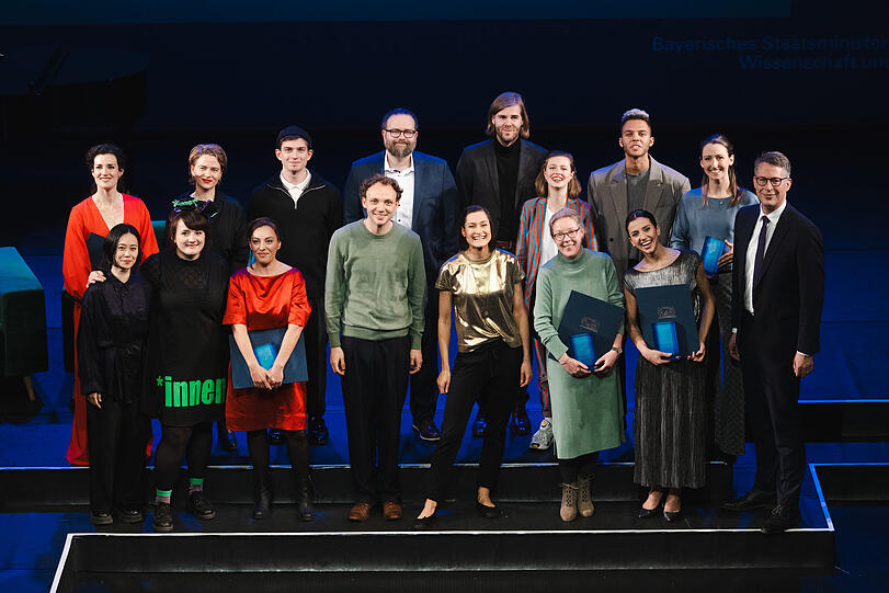 Gruppenfoto mit gegendertem Kleid. Die Preisträgerinnen und Preisträger mit Kunstminister Markus Blume (rechts).