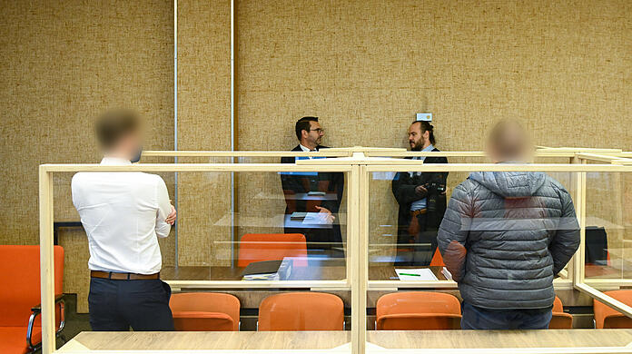 Die zwei Angeklagten (l und r) stehen im Gerichtssaal, während sich die Anwälte Sebastian Weber (2.v.l.) und Christian Barthelmes (2.v.r.) unterhalten. Am Dienstag fiel das Urteil gegen die beiden suspendierten Beamten.