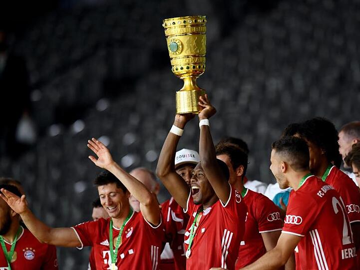 David Alaba jubelt mit der Trophäe nach dem Spiel. Foto: Annegret Hilse/Reuters/POOL/dpa/Archivbild