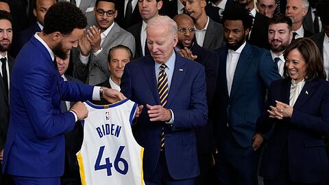 Warriors-Superstar Stephen Curry (l) überreicht Joe Biden ein Trikot.