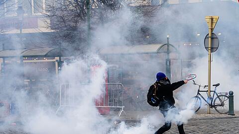 Ein Demonstrant schl&auml;gt bei den Protesten in Br&uuml;ssel gegen einen Tr&auml;nengasbeh&auml;lter.