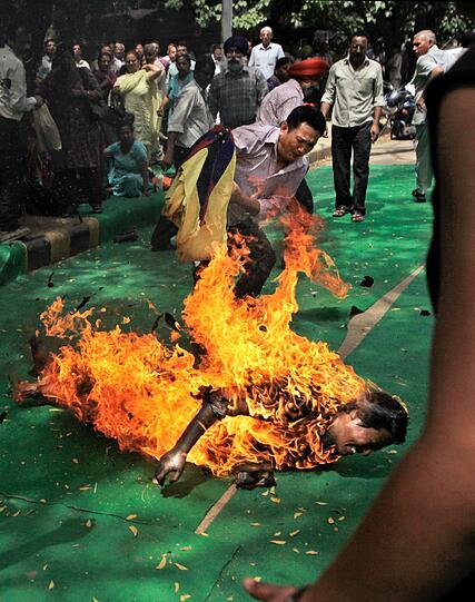 Auf einer Demonstration in Indien löscht ein Teilnehmer einen tibetischen Aktivisten, der sich selbst in Brand gesteckt hat.