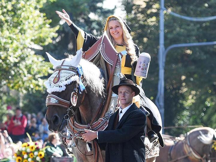Das Münchner Kindl, eine Frau in schwarz-gelber Mönchskutte, reitet beim Einzug der Wiesenwirte mit einem Bierkrug in der Hand zum Oktoberfest.