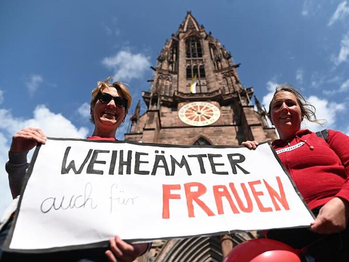 Zwei Frauen der Initiative Maria 2.0 werben vor dem Freiburger Münster für "Weiheämter auch für Frauen".
