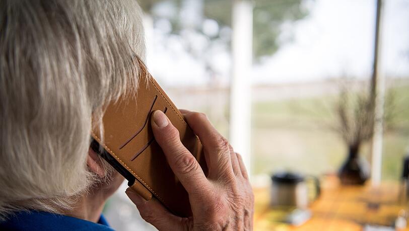 Eine alte Frau telefoniert. Telefonbetrüger überrumpeln gern mit falschen Geschichten und ergaunern viel Geld. (Symbolbild)