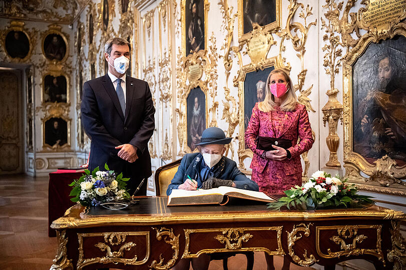 Königin Margrethe II. von Dänemark (M) trägt sich in der Residenz München neben Markus Söder (CSU), Parteivorsitzender und Ministerpräsident von Bayern, in das Gästebuch der Bayerischen Staatsregierung ein. Rechts steht Söders Frau Karin Baumüller-Söder.