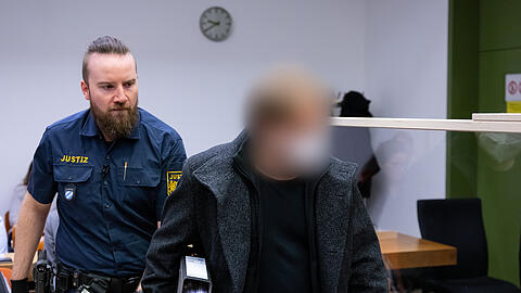 Der wegen sexuellen Missbrauch von Kindern angeklagte Mann (r.) wird im Landgericht München I in den Gerichtssaal geführt.