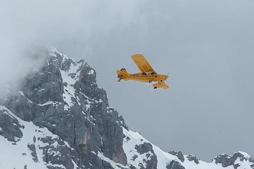 Ein quietschgelber Flieger bei den Bergspitzen des Zugspitzmassivs