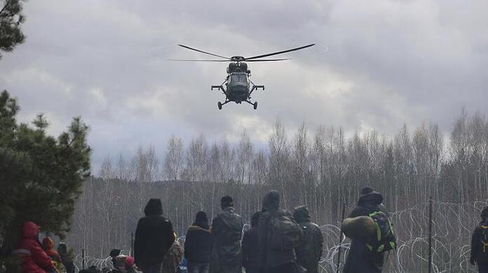 Ein polnischer Militärhubschrauber fliegt über eine Gruppe Migranten, die sich an der weißrussisch-polnischen Grenze versammelt haben.