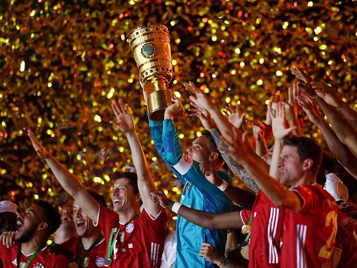 Münchens Torhüter Manuel Neuer hält die Trophäe jubelt mit dem DFB-Pokal.