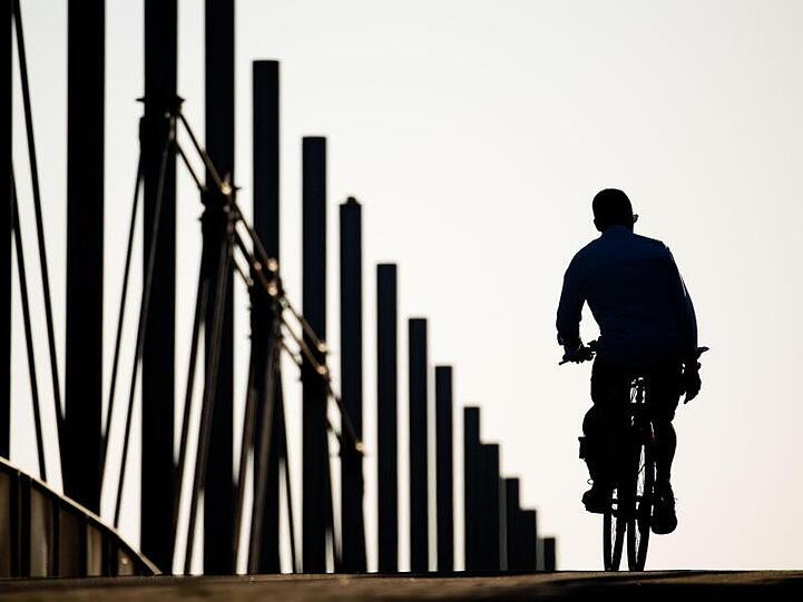 Ein Fahrradfahrer fährt am frühen Morgen über eine Brücke im niedersächsischen Laatzen.