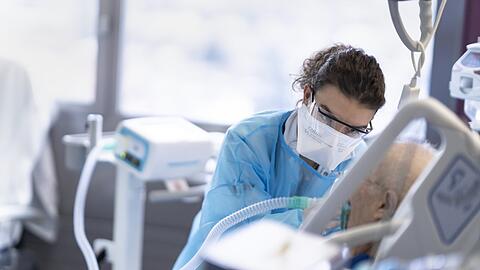Eine medizinische Mitarbeiterin pflegt eine Person mit Covid-19-Erkrankung.