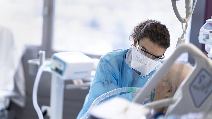 Eine medizinische Mitarbeiterin pflegt eine Person mit Covid-19-Erkrankung.