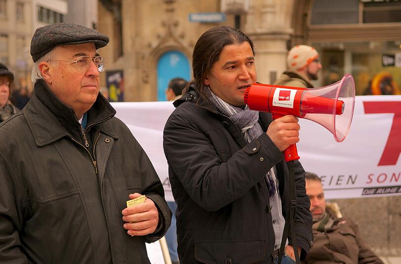 Der Linken-Stadtrat Orhan Akman (r.) mit Megafon bei einer Kundgebung auf dem Marienplatz.