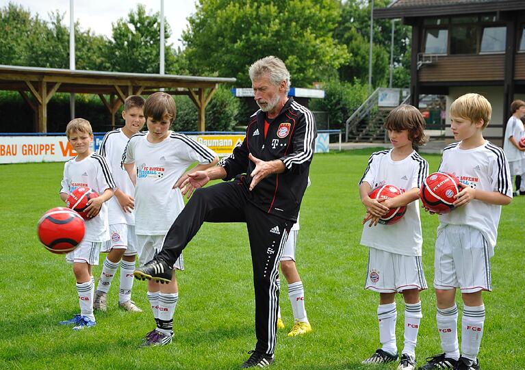 Bayerns Fußball-Legende Paul Breitner zeigt den Kids beim Fußball-Camp, wie es geht.