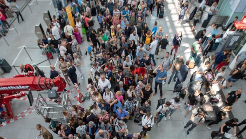 Fluggäste stehen in einem Terminal unter einer Anzeigetafel, auf der viele Flüge als gestrichen angezeigt sind. Foto: Peter Kneffel Fluggäste stehen in einem Terminal unter einer Anzeigetafel, auf der viele Flüge als gestrichen angezeigt sind. Foto: Peter Kneffel