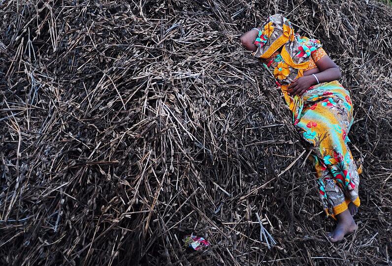 Während des Eunuchen-Fests in Indien schläft eine Frau auf einem Holz-Gras-Haufen.