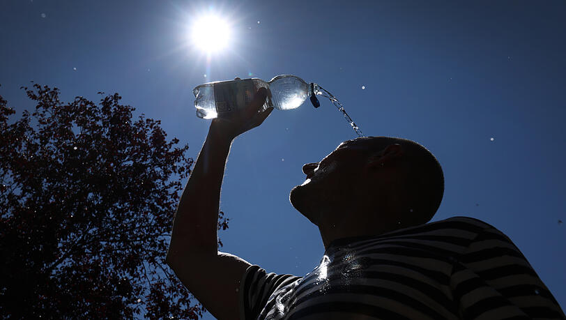 Ein Mann lässt sich zur Erfrischung Wasser über das Gesicht laufen. Die Hitzewelle ist bald vorbei. Ein Mann lässt sich zur Erfrischung Wasser über das Gesicht laufen. Die Hitzewelle ist bald vorbei.
