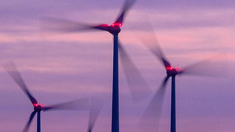Mit Signallampen beleuchtete Windräder drehen sich nach Sonnenuntergang.