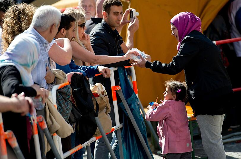 Eine Frau gibt einem Flüchtlingskind und seiner Mutter am Münchner Hauptbahnhof ein paar Spenden.