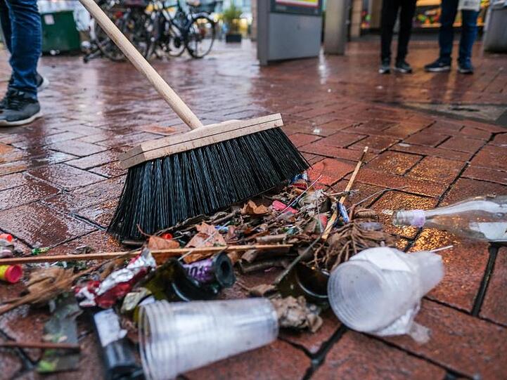 Ein Mann fegt Abgebrannte Feuerwerkskörper und andere Überreste der Silvesternacht zusammen. Foto: Clemens Heidrich/Archiv
