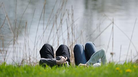 Menschen liegen am Ostermontag bei Sonnenschein auf einer Wiese im Clara-Zetkin-Park in Leipzig.