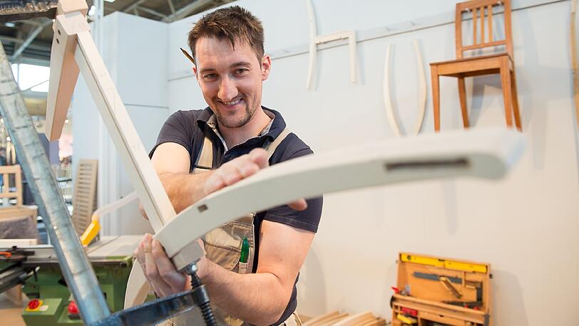 Schreiner Philipp von Manz aus Breitenberg zeigt auf der Handwerksmesse, wie er Möbel fertigt.